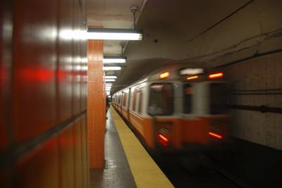 Orange train speeding through dimly lit subway station, photo with motion blur.