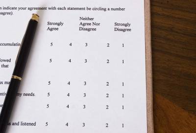 Survey form with pen, displaying agreement scale, on a wooden table.
