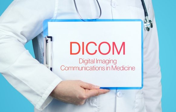 Doctor holding clipboard with "DICOM" text, against blue background, in photo.