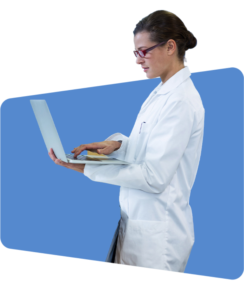 A woman in a white lab coat uses a laptop, blue background.