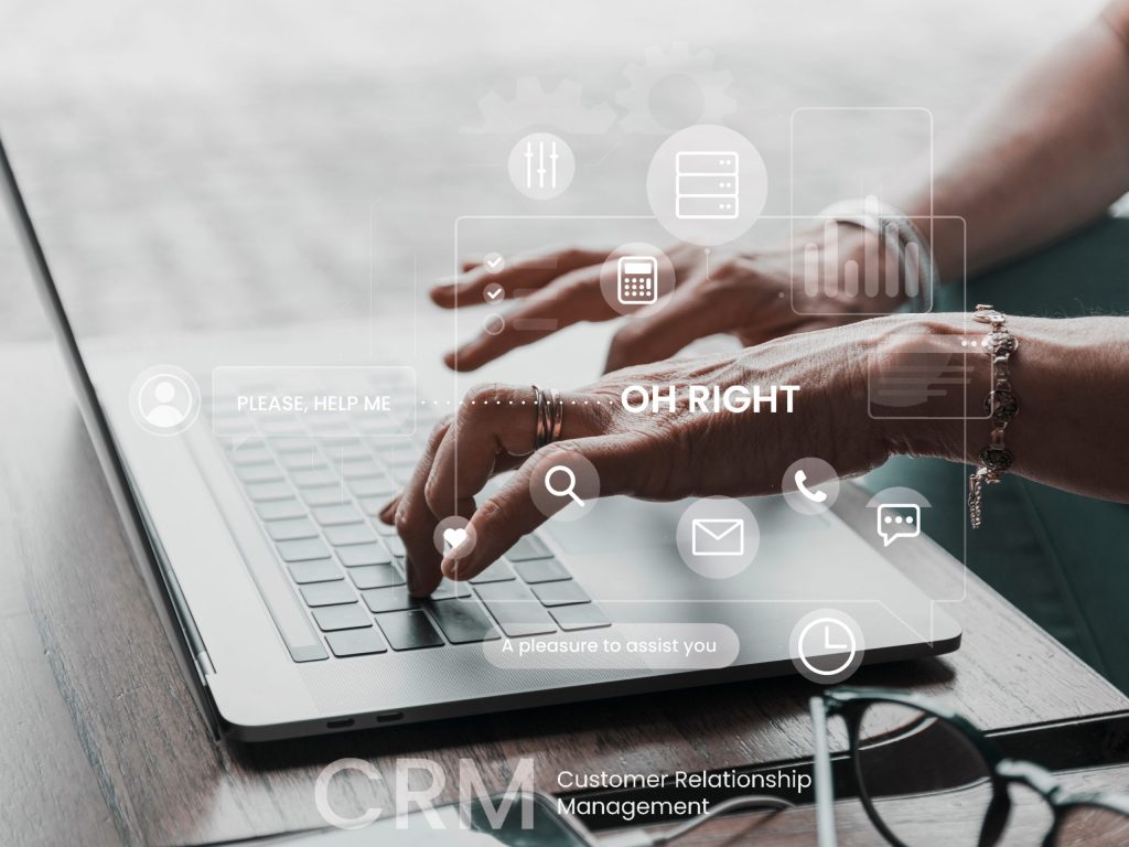 Hands typing on a laptop with CRM-related icons and text overlay.